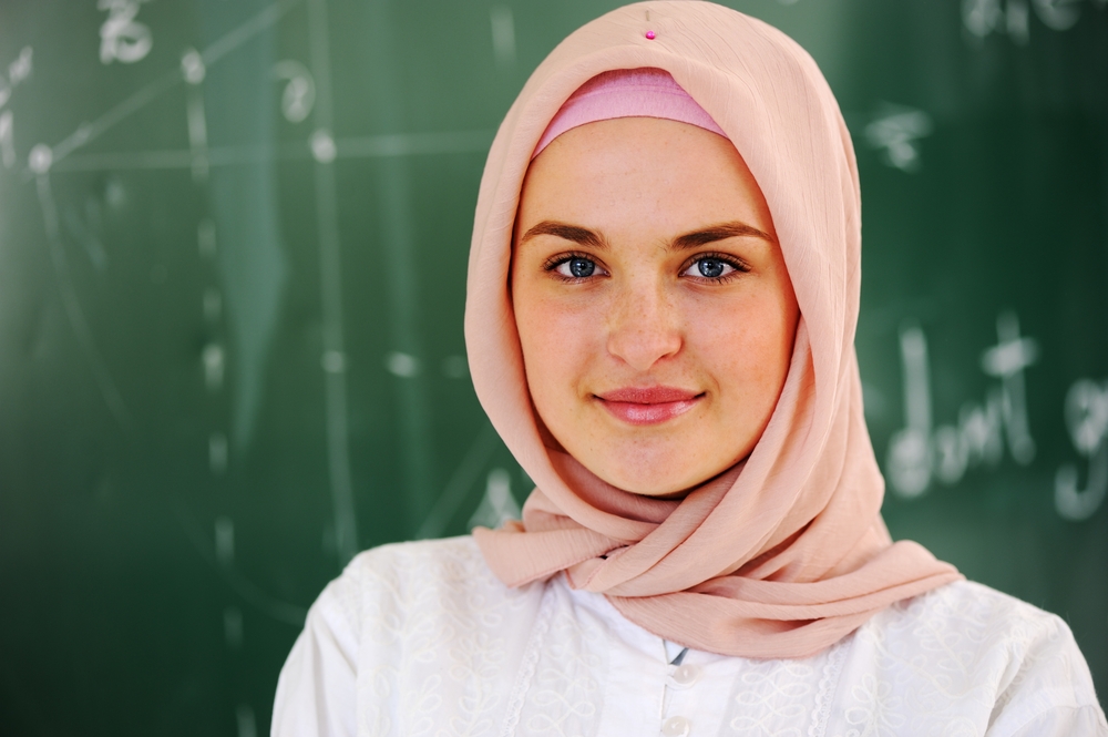 Arabic Muslim teenage student inside the high school classroom posing on board