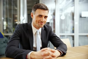 Happy businessman sitting at the table in office