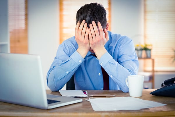 Stressed businessman with head in hands at office-1