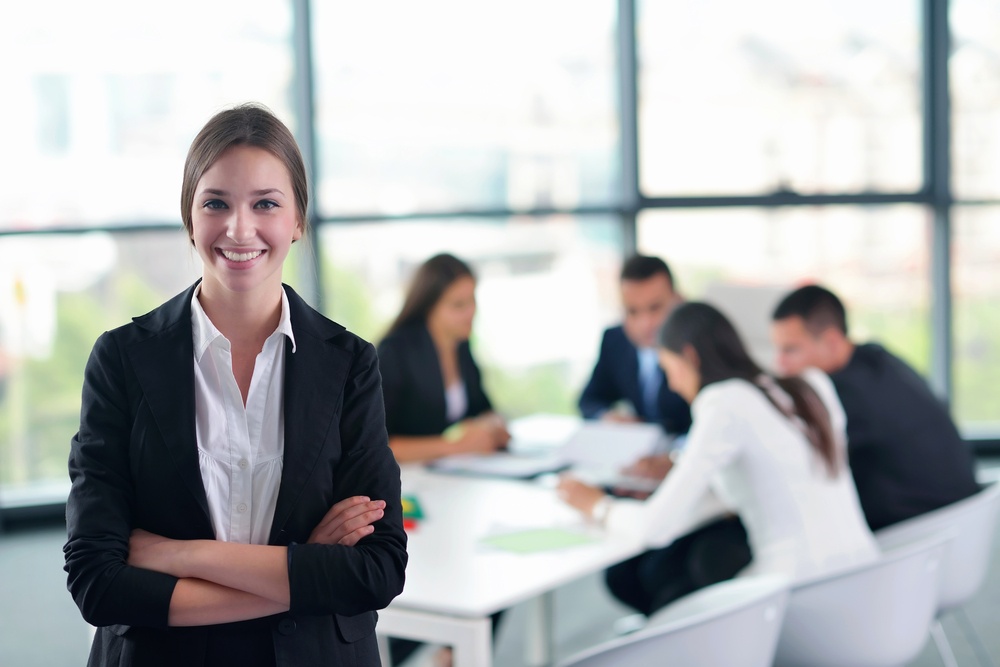 happy young business woman  with her staff,  people group in background at modern bright office indoors.jpeg